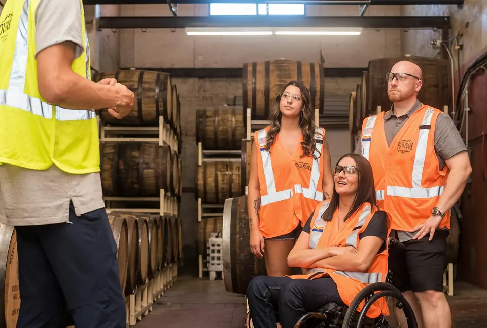 Lagerteam in Warnwesten im Fasslager (zwei Frauen, ein Mann)
